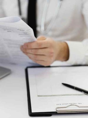 Close-up of a doctor holding medical records and reviewing a clipboard, symbolizing patient documentation and record management.